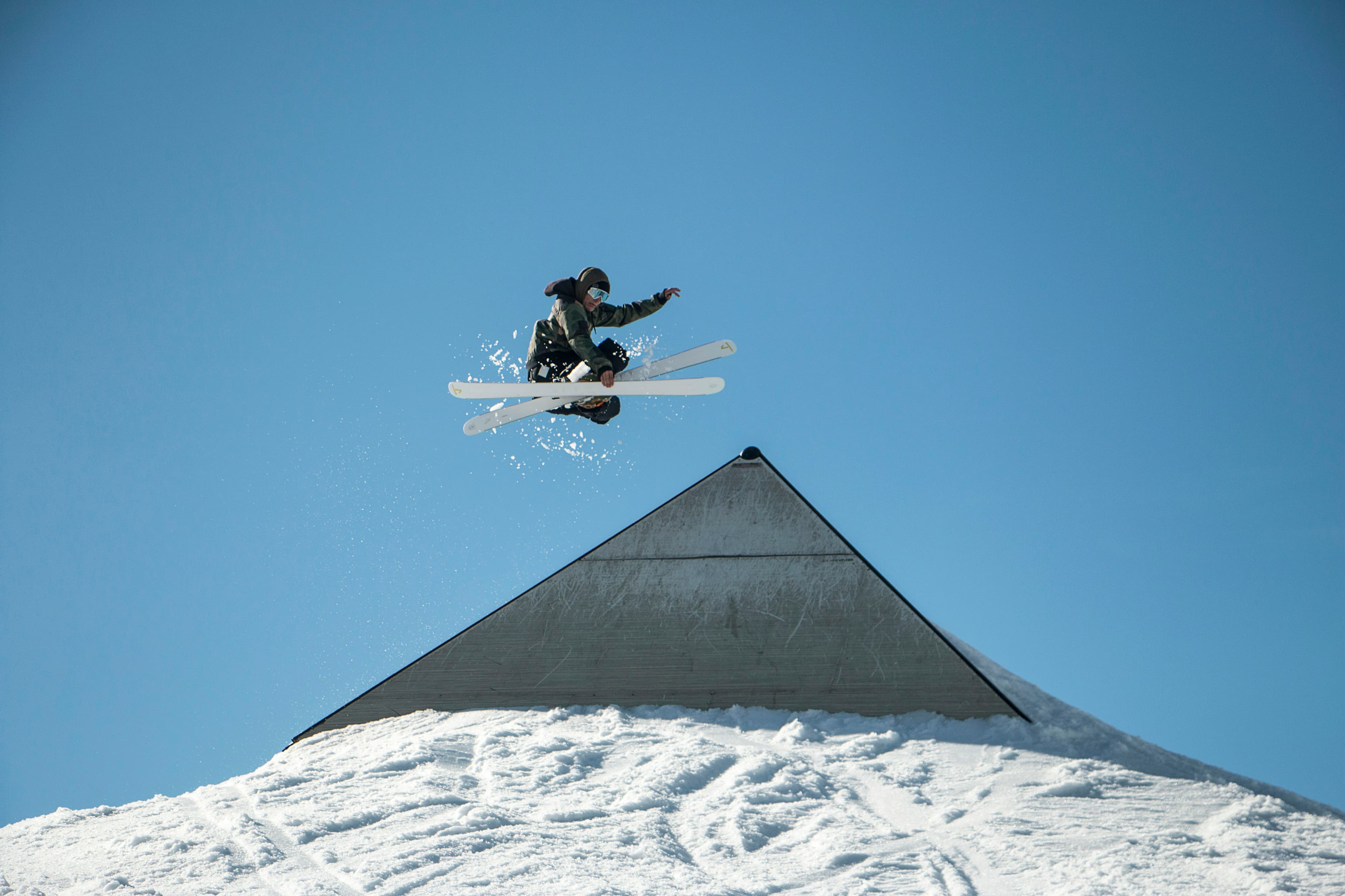 Freeskiër maakt een sprong tegen een blauwe lucht in Laax