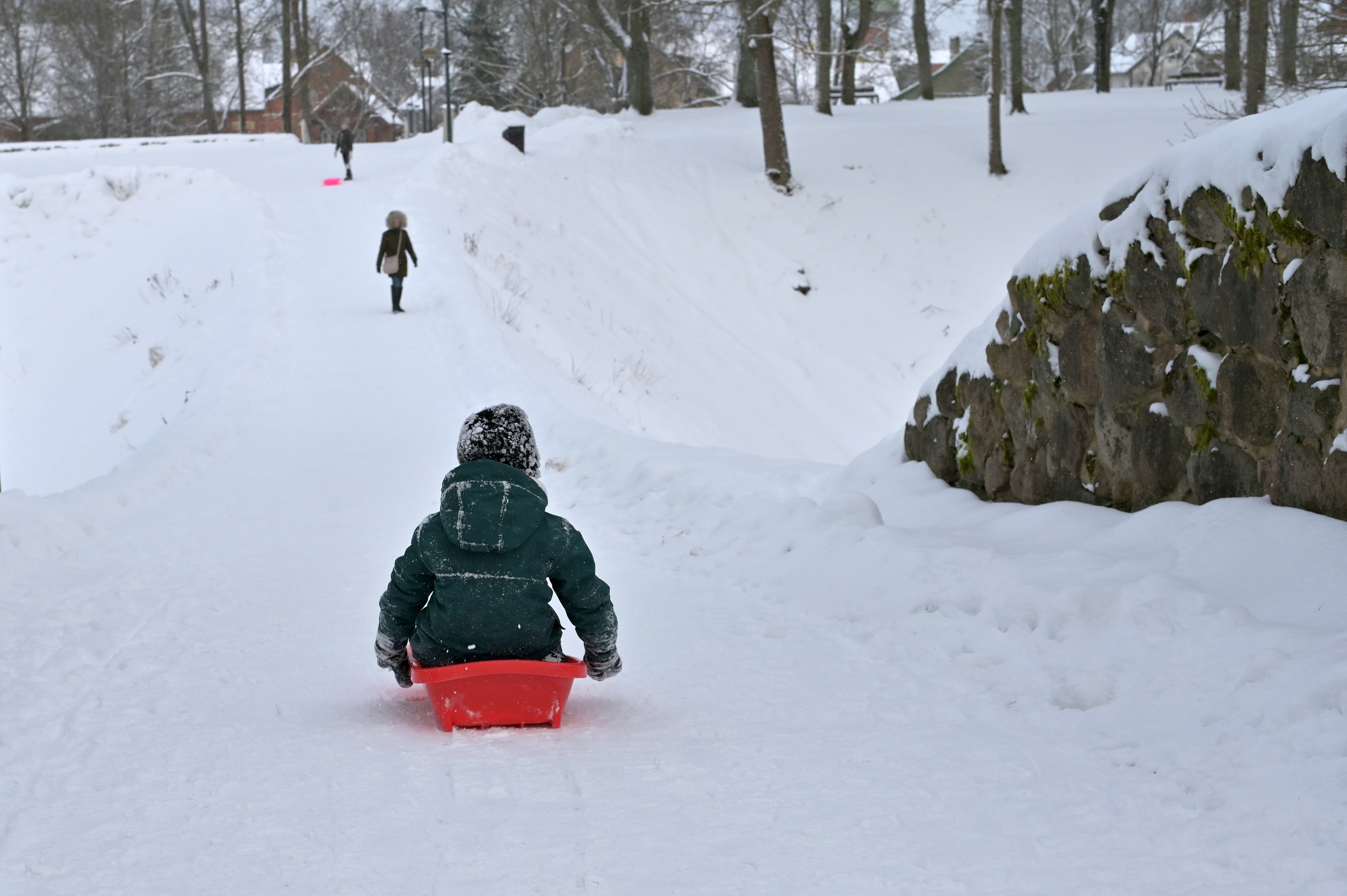 Kind op een rode slee in een besneeuwd winterlandschap