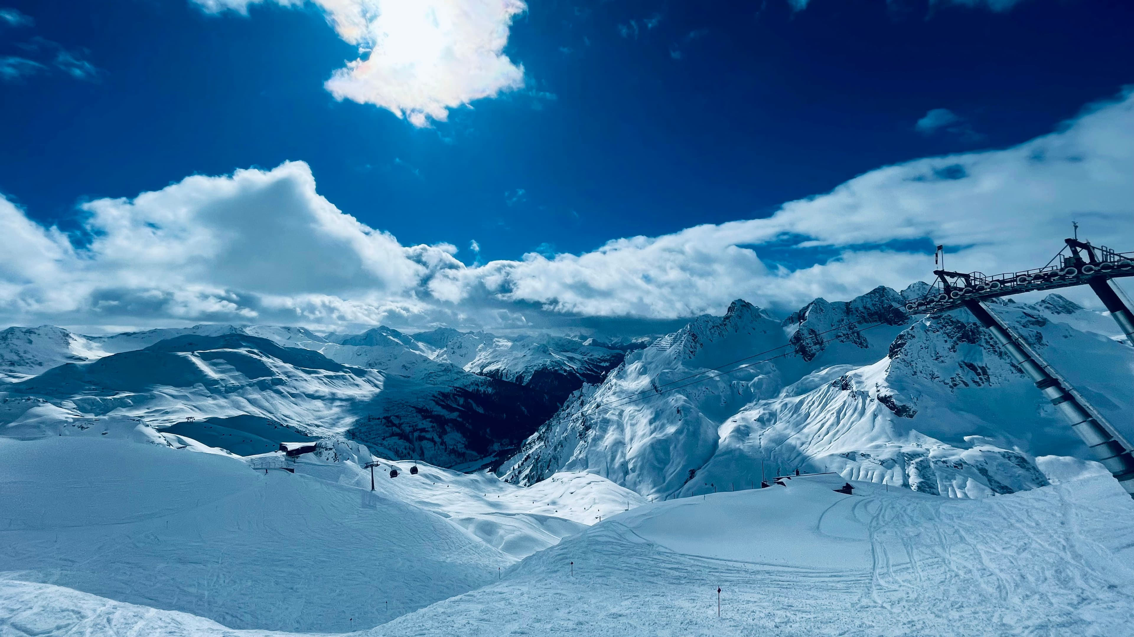 Brede sneeuwhellingen met skilift onder een blauwe lucht aan de Arlberg