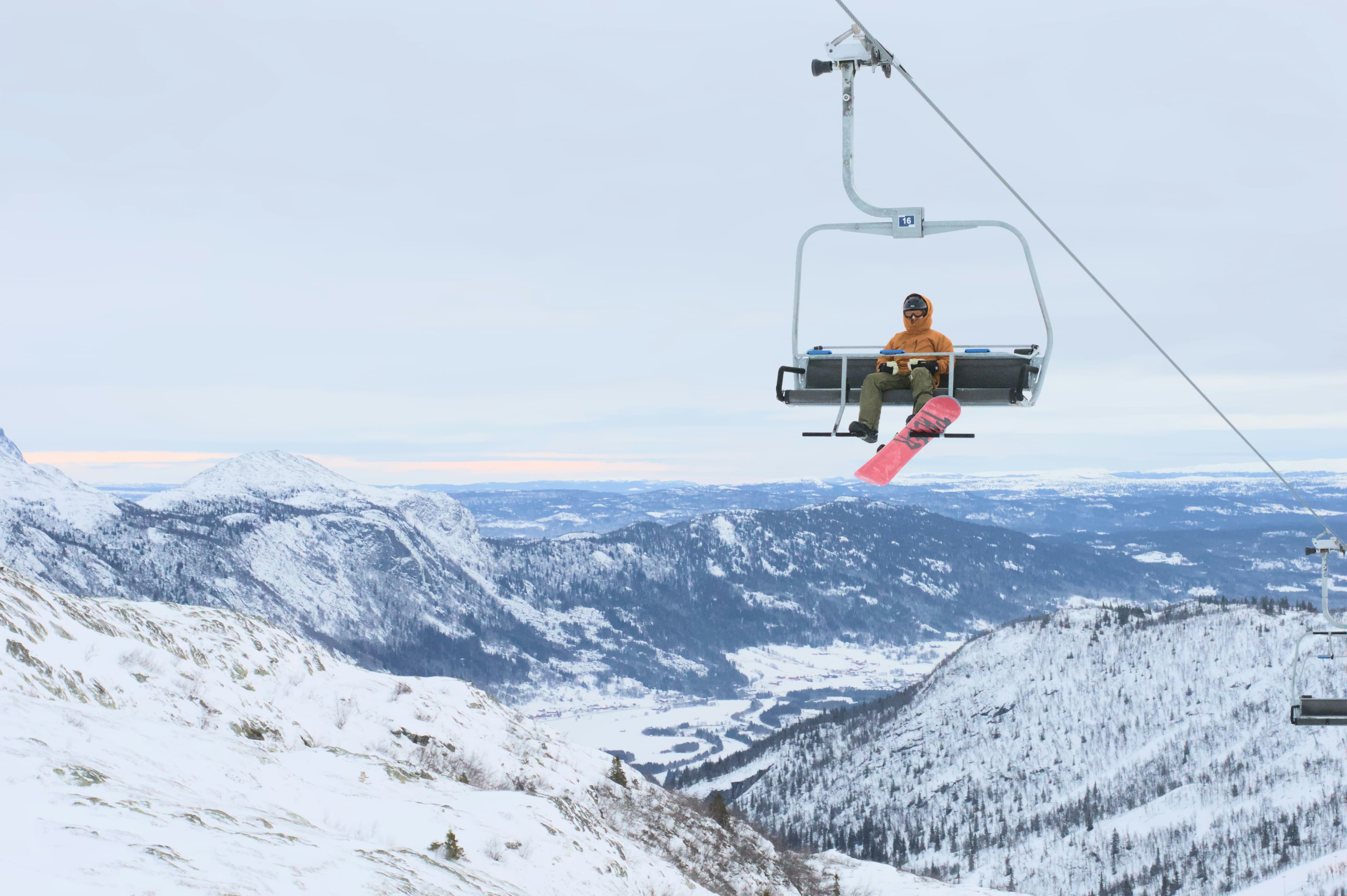 Snowboarder in een stoeltjeslift boven het besneeuwde dal van Hemsedal