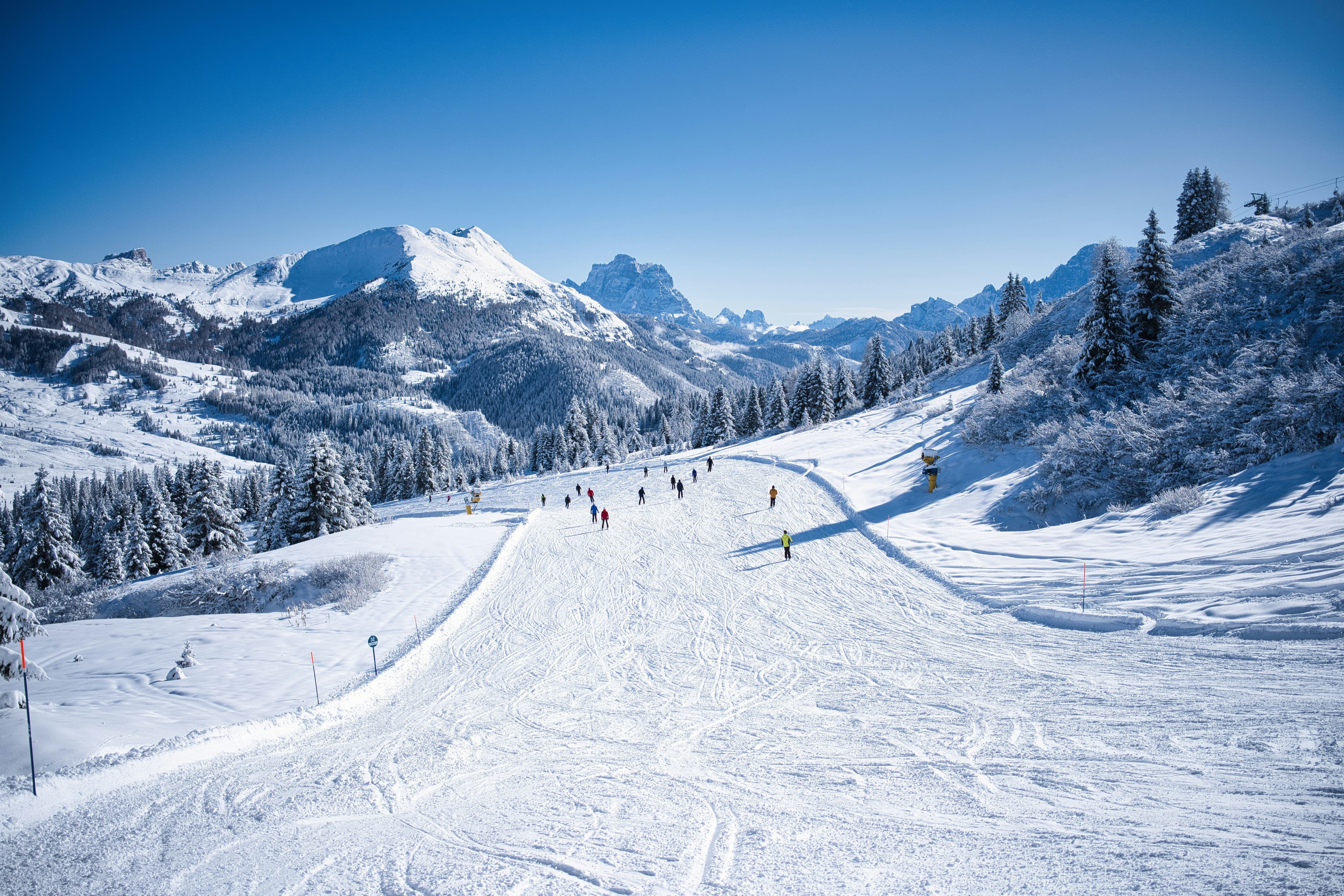 Skiërs op een brede, zonnige piste