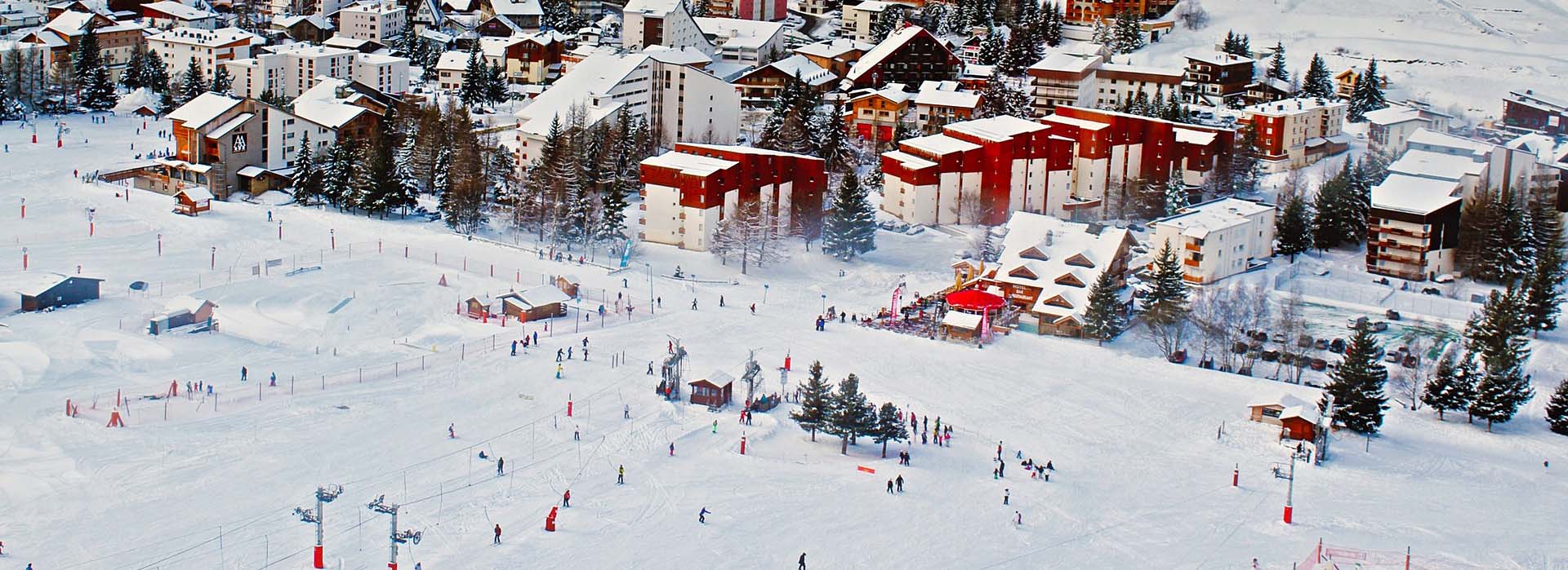 Zonnig skidorp met chalets en pistes in de Franse Alpen