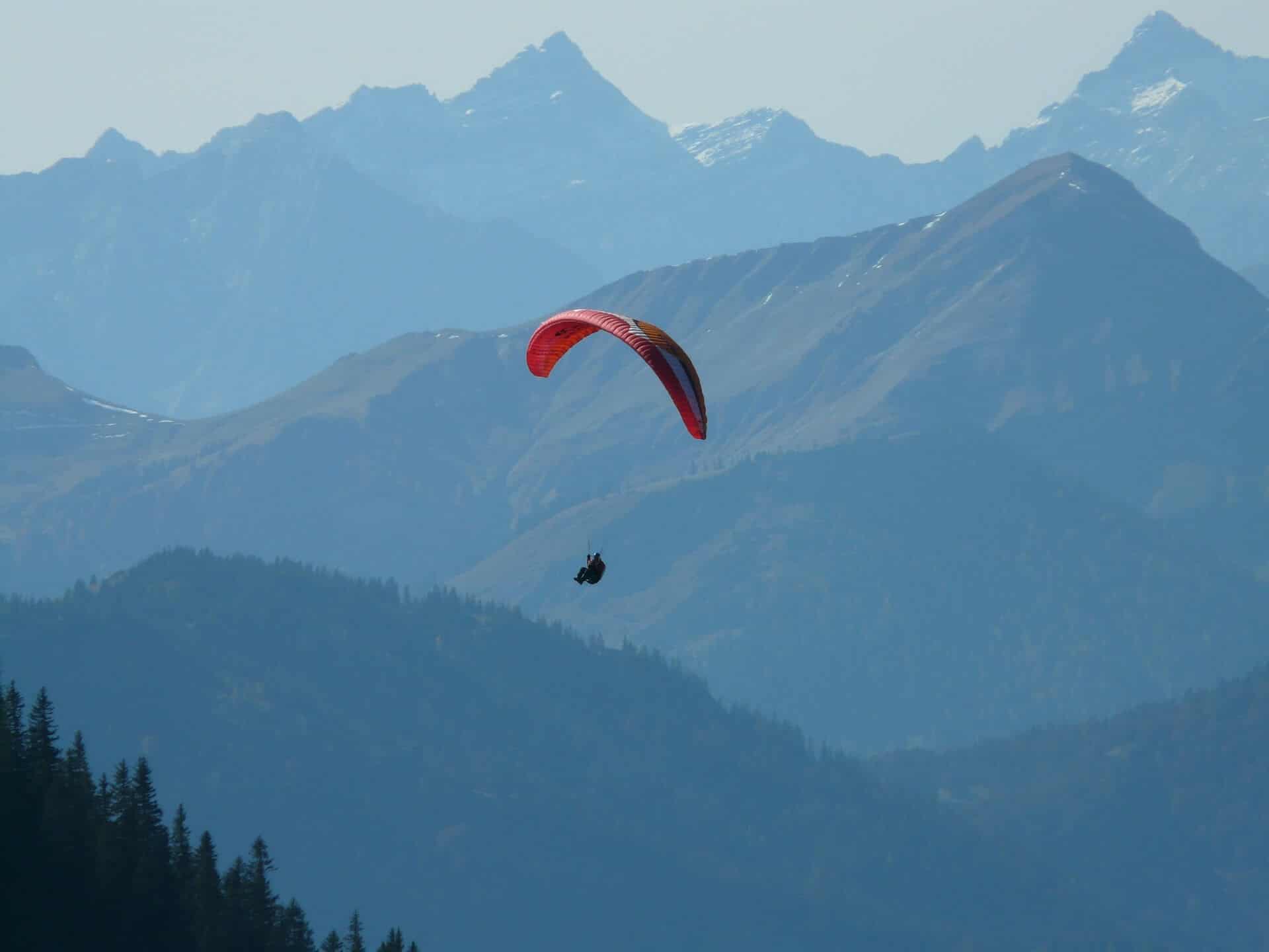 Paraglider zweeft boven blauwe bergruggen